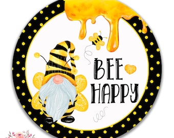 Op de afbeelding: Een rond metalen bord met een zwarte en gele stippenachtergrond. Een bijengnoom met gele en zwarte strepen en een witte baard bevindt zich in het midden. Het bord zegt "Bee Happy" met een klein hartje naast het woord "Bee".