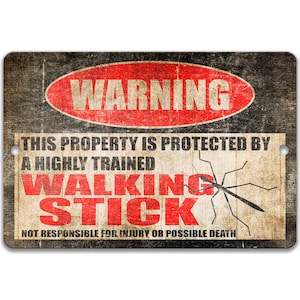 May include: A rectangular metal sign with a distressed finish. The sign features the word "WARNING" in a red oval, and text stating "THIS PROPERTY IS PROTECTED BY A HIGHLY TRAINED WALKING STICK". A black insect graphic is also present.