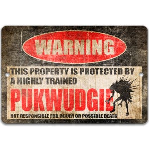 May include: A rectangular metal sign with a distressed, vintage look. The sign features the word "WARNING" in a red oval, and text stating "THIS PROPERTY IS PROTECTED BY A HIGHLY TRAINED PUKWUDGIE". A black creature illustration is on the right.