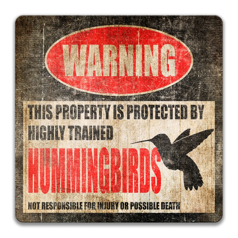 Puede incluir: Un cartel de advertencia con un c&iacute;rculo rojo y la palabra "WARNING" en blanco. El cartel dice "This property is protected by highly trained hummingbirds. Not responsible for injury or possible death." El cartel tiene un aspecto desgastado y vintage.