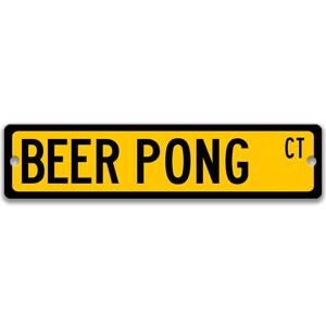 以下が含まれることがあります： 「BEER PONG」という文字と右上に「CT」という略語が書かれた黄色と黒の看板です。
