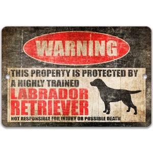 May include: A warning sign with a red circle and the word "WARNING" in white. The sign reads "This property is protected by a highly trained Labrador Retriever. Not responsible for injury or possible death." The sign has a distressed, vintage look and features a black silhouette of a Labrador Retriever.