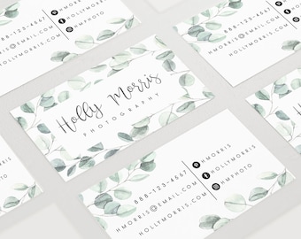 May include: White business card with a watercolor design of green eucalyptus leaves. The text "Holly Morris Photography" is written in cursive script. The phone number, email address, and social media handles are listed on the card.
