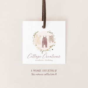 May include: A premade logo design for a business called "Cottage Creations" that sells newborn clothing. The logo features a watercolour illustration of three baby clothes hanging on a clothesline with a floral wreath around them. The text "Cottage Creations" is written in cursive below the illustration, and the text "newborn clothing" is written in a smaller font below that.