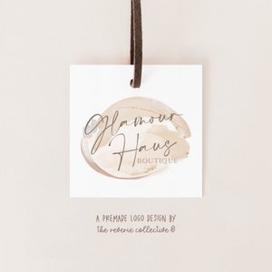May include: A white tag with a brown leather string attached. The tag features a logo design with the text "Glamour Haus Boutique" in a handwritten font on a beige and gold watercolor background.