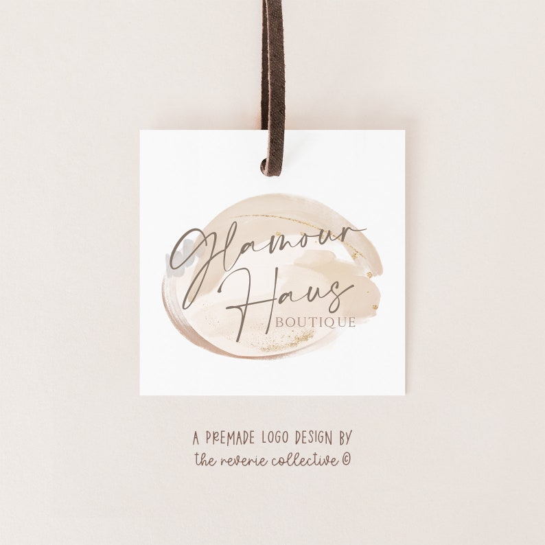 May include: A white tag with a brown leather string attached. The tag features a logo design with the text "Glamour Haus Boutique" in a handwritten font on a beige and gold watercolor background.