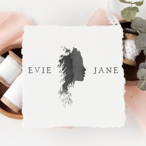 May include: A white card with a black silhouette of a woman's face with a tree design. The text "EVIE JANE" is printed on the card.