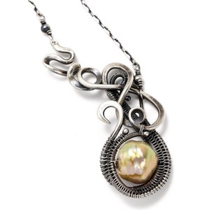 May include: A silver necklace with a large, iridescent pearl pendant. The pendant is surrounded by intricate wirework, creating a unique and modern design.