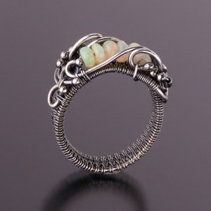 Peut inclure: Une bague en fil d'argent avec une rangée de pierres d'opale serties dans la bande.