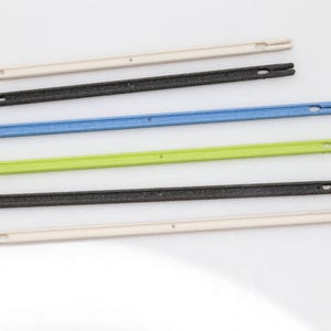 May include: Five different colored plastic strips with holes at each end. The strips are white, black, blue, green, and black.