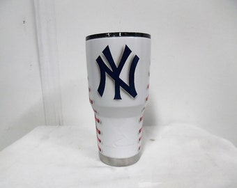 May include: White stainless steel tumbler with a baseball stitching design and a blue and white New York Yankees logo.