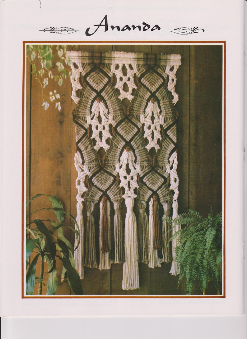 May include: A macrame wall hanging with a geometric pattern in shades of brown, beige, and white. The hanging has a fringe of tassels in brown and white.