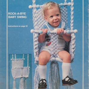 Könnte beinhalten: Eine blaue und weiße gehäkelte Babyschaukel mit einem Baby darin. Die Schaukel hat Holzperlen und Quasten. Die Anleitung zum Herstellen der Schaukel befindet sich auf Seite 22.