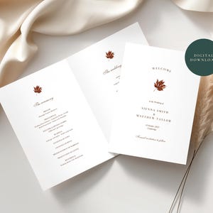 May include: A white wedding invitation card set featuring a dark red maple leaf illustration. The text reads Welcome at the wedding of Sienna Smith & Matthew Taylor, 21 October 2027, Cambridge. The inner card lists The Ceremony details. A dark green circle reads Digital Download.