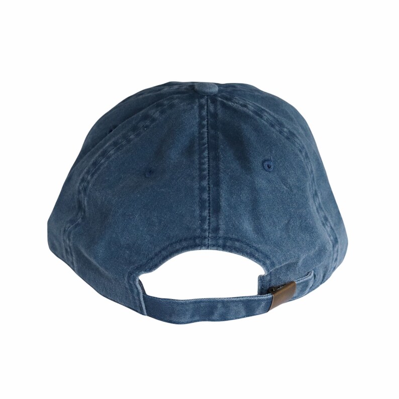 May include: A solid navy blue baseball cap with a curved brim. The back of the cap features an adjustable strap with a metal clasp. The cap is made of a soft, washed fabric.