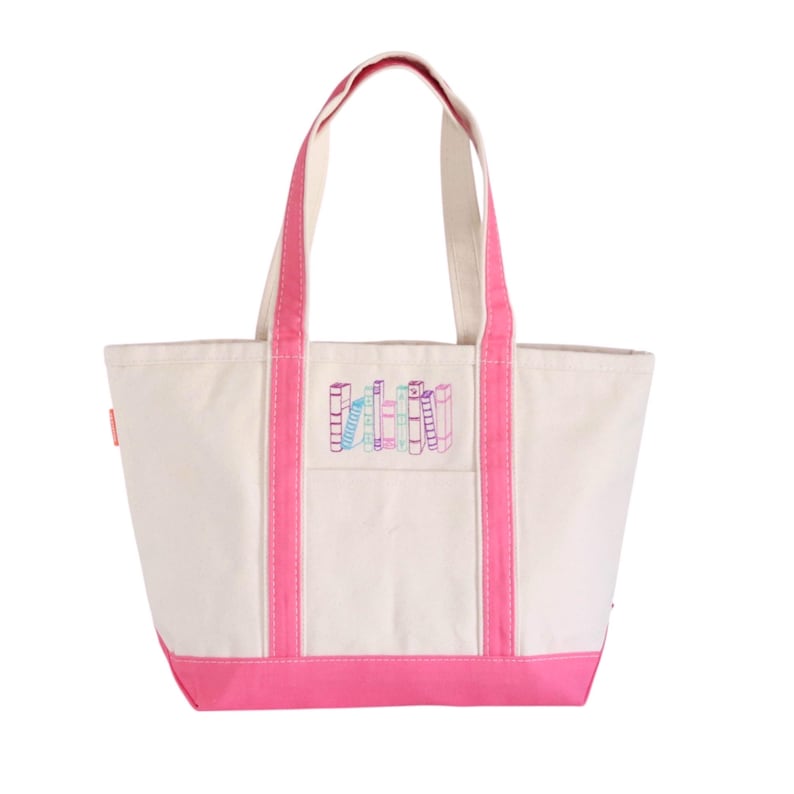 May include: A canvas tote bag with a cream-colored body, pink trim, and handles. The bag features an embroidered design of colorful books. The tote bag is a practical accessory for carrying books, groceries, or personal items.