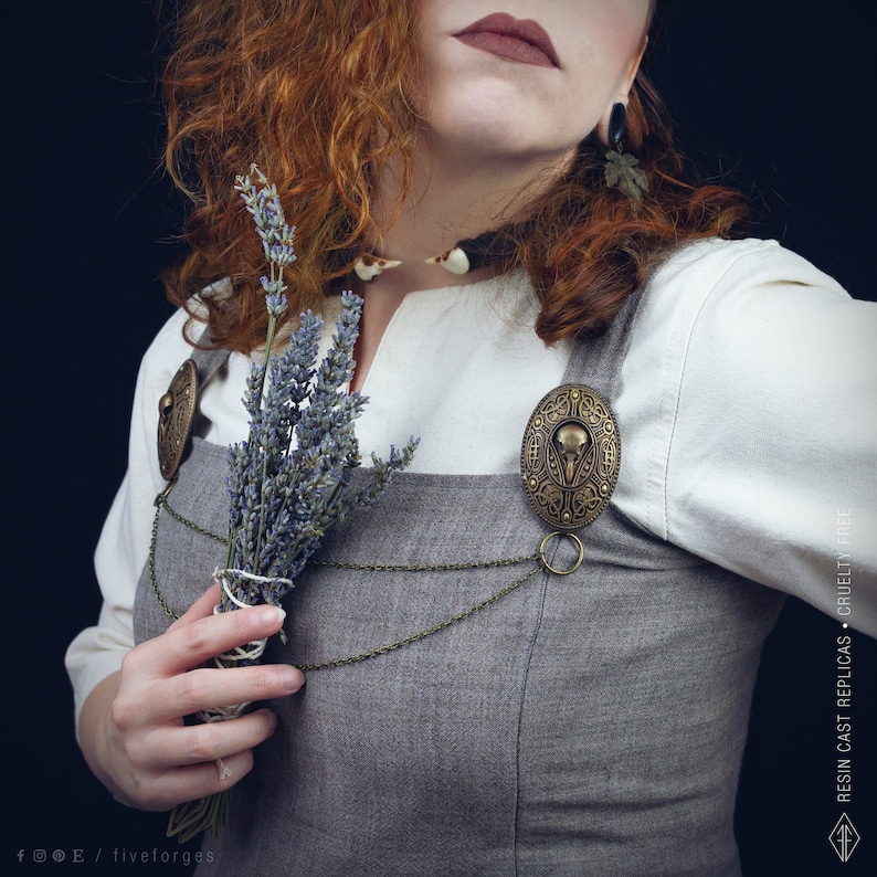 Two hand painted brass brooches with a bird crow skull design, connected by two bronze chains. This pins are perfect for historical reenactments, cosplay, Viking and Norse style costumes. Medieval wedding dress.