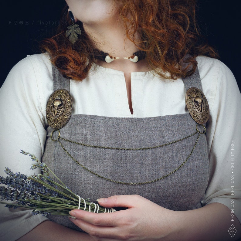 Two hand painted brass brooches with a bird crow skull design, connected by two bronze chains. This pins are perfect for historical reenactments, cosplay, Viking and Norse style costumes. Medieval wedding dress.