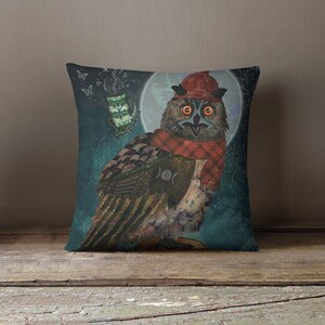 May include: Decorative square pillow featuring a whimsical owl illustration. The owl wears a red hat and scarf, set against a teal background with a full moon and a floating mug. The owl has orange eyes and detailed feather patterns.
