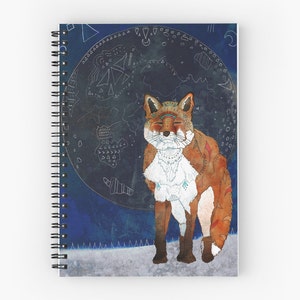 May include: Spiral notebook featuring a detailed illustration of a fox with closed eyes, adorned with tribal-inspired patterns. The fox is set against a dark blue background with a celestial design. The notebook has a white spiral binding.