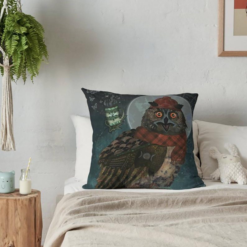 May include: Square decorative pillow featuring a whimsical owl illustration. The owl is depicted with a red hat and scarf, set against a dark blue background with a full moon and stars. The pillow adds a touch of fantasy to any room.