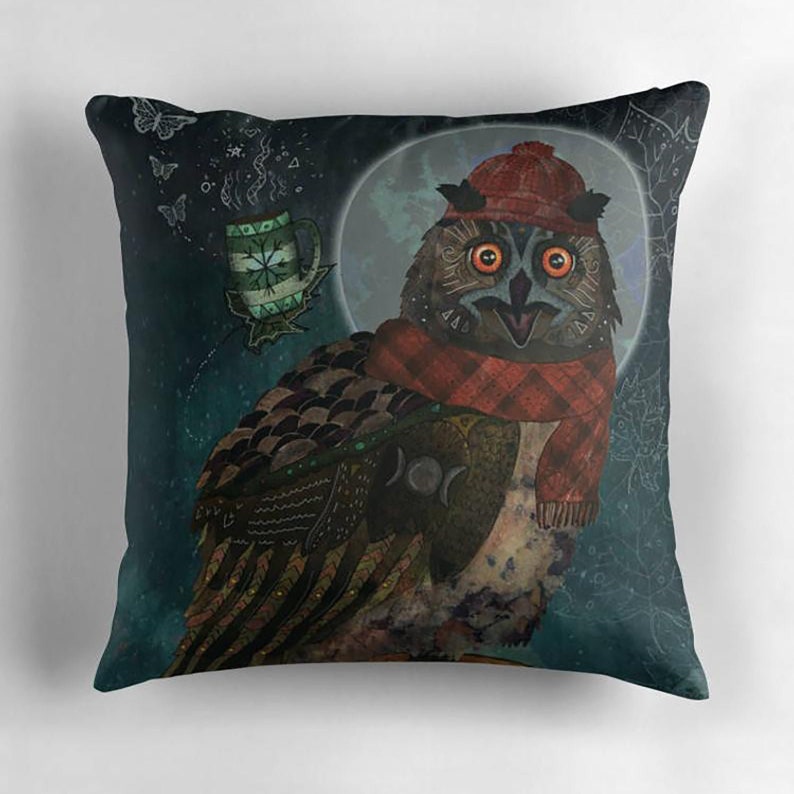 May include: Square decorative pillow featuring an owl illustration. The owl wears a red hat and scarf, with a mug of tea and a full moon in the background. The pillow has a dark teal background with a whimsical design.