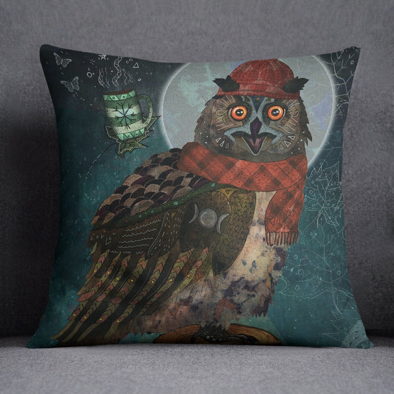 May include: Decorative square pillow featuring a whimsical owl illustration. The owl wears a red hat and scarf, with a mug of tea and a full moon in the background. The owl has orange eyes and detailed feather patterns. The pillow is likely made of soft fabric.
