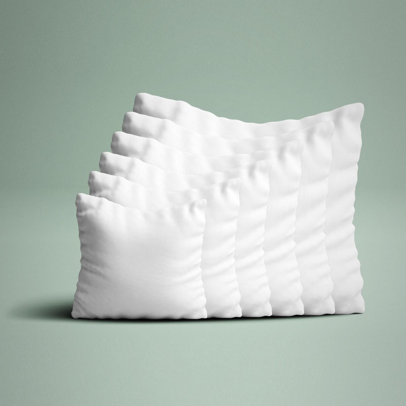 May include: A stack of seven square, white pillows. The pillows are arranged in a diagonal line, with each pillow slightly behind and to the right of the previous one. The pillows have a soft, textured appearance, suggesting a comfortable filling.