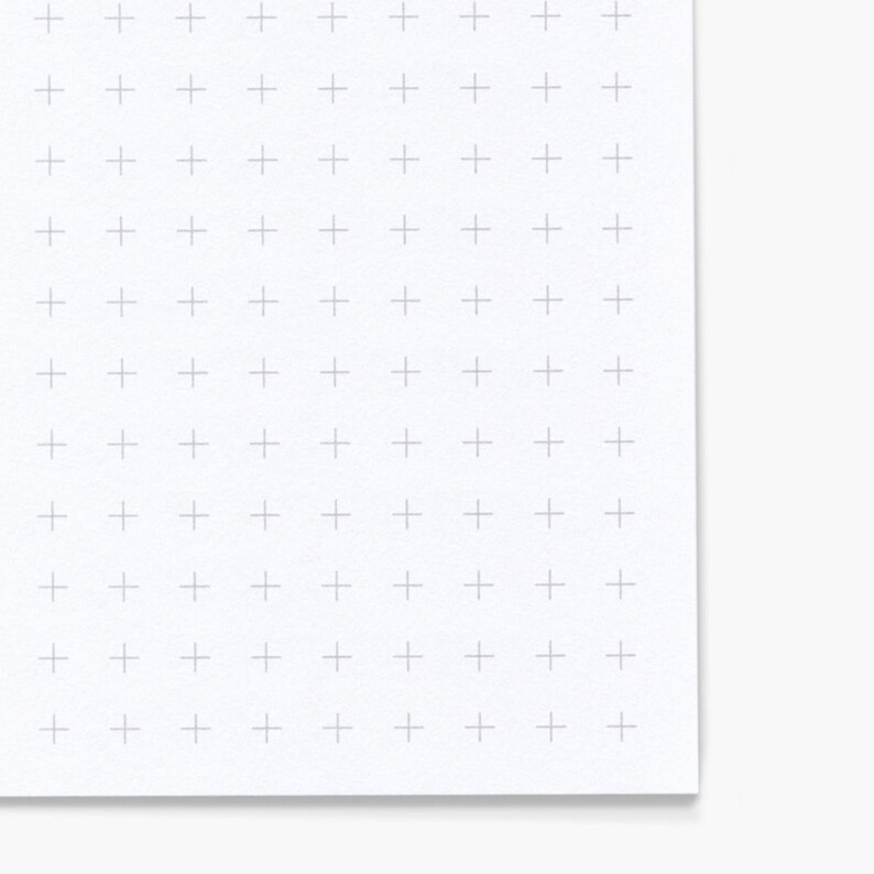 May include: A white sheet of paper with a grid of light gray plus signs. The paper has a slightly textured surface and a corner is folded over, revealing a clean white edge.