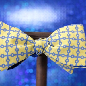 Op de afbeelding: Een gele vlinderdas met een blauw geometrisch patroon.