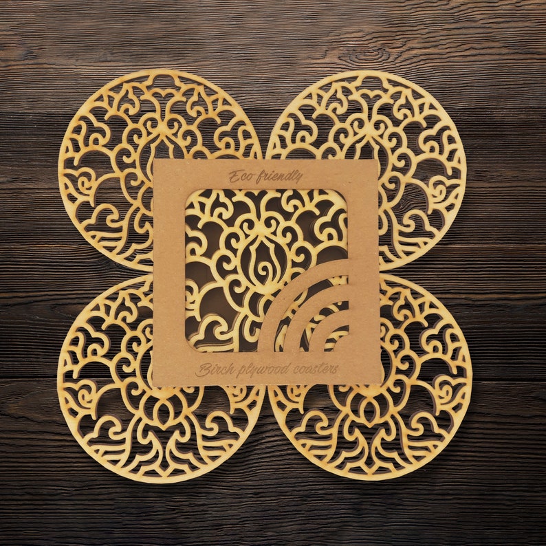 A set of wooden laser-cut coasters in a cardboard box. Placemats are cut out with floral motifs. The set includes 4 round coasters.