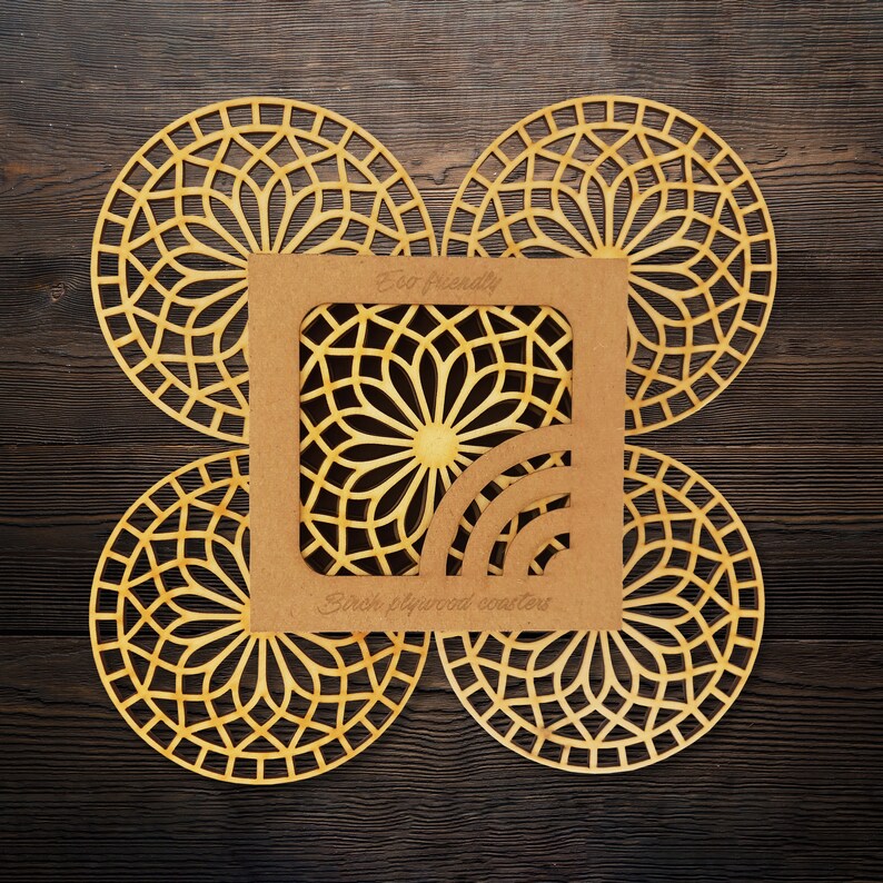 A set of wooden laser-cut coasters in a cardboard box. Placemats are cut out with modern flower motifs. The set includes 4 round drink coasters.