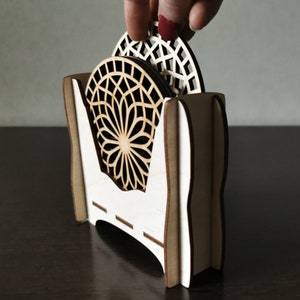 A set of wooden laser cut coasters in a wooden stand. Placemats are cut out with modern flower motifs. The set includes 4 round drinking coasters.