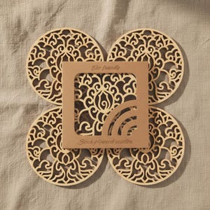A set of wooden laser-cut coasters in a cardboard box. Placemats are cut out with floral motifs. The set includes 4 round coasters.