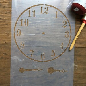Puede incluir: Una plantilla de pl&aacute;stico transparente para pintar una esfera de reloj con n&uacute;meros romanos. La plantilla incluye dos manecillas de reloj.
