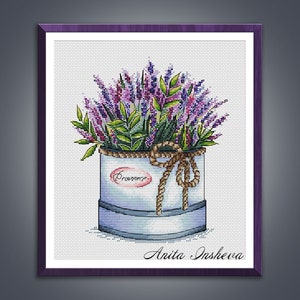 May include: A cross-stitch pattern of a bouquet of lavender flowers in a blue and white tin container with a rope bow and the word "Provence" on the side. The artist's signature, "Anita Insheva", is at the bottom of the image.