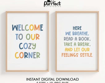 May include: Two framed prints with text. The left print reads "WELCOME TO OUR COZY CORNER" in blue, orange, green, and yellow. The right print says "HERE WE BREATHE, READ A BOOK, TAKE A BREAK, AND LET OUR FEELINGS SETTLE" in blue, green, orange, and yellow.