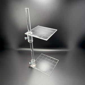 Peut inclure: Un présentoir en acrylique transparent avec deux étagères réglables. Le présentoir est en acrylique transparent et présente un motif en grille sur les étagères.