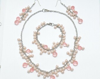 Parure avec un collier, un bracelet et des boucles d'oreilles de perles roses pâles et roses