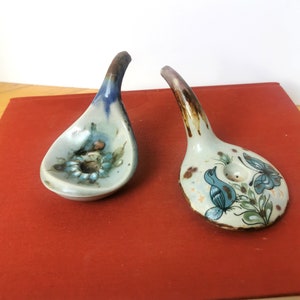 May include: Two ceramic spoons with blue and brown glaze. The spoons are decorated with floral and bird designs.