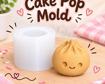 May include: A translucent cylindrical silicone cake pop mold next to a tan, round, dumpling-shaped cake pop with a smiling face. The text "Cake Pop Mold" is printed in brown above the items, surrounded by small pink heart and dash graphics.