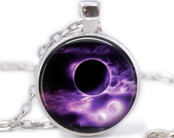 May include: A silver chain necklace with a round pendant featuring a black hole and purple nebula in space.