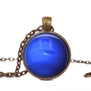 May include: A blue glass pendant necklace with a bronze chain. The pendant features a blue and white image of the planet Neptune.