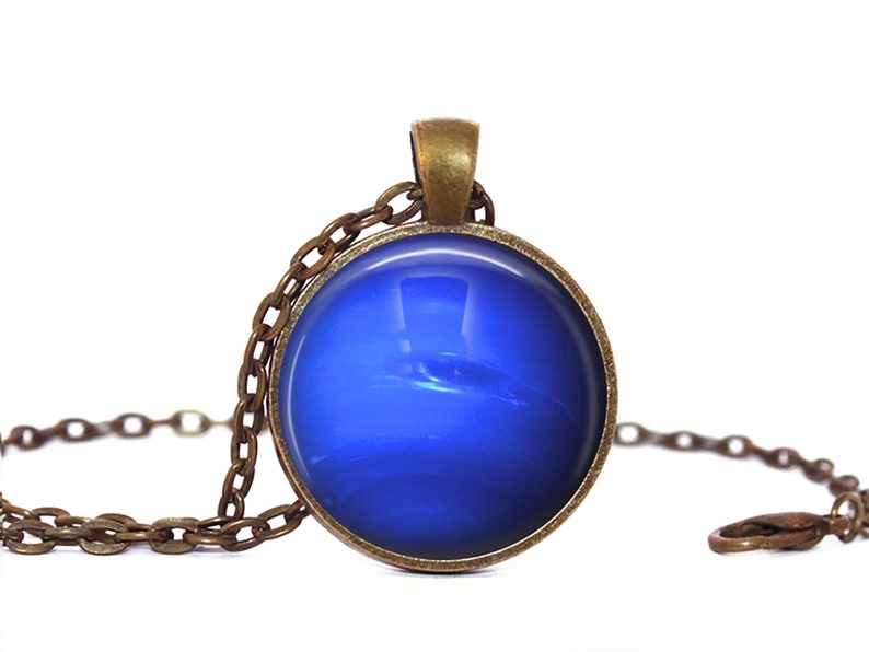 May include: A blue glass pendant necklace with a bronze chain. The pendant features a blue and white image of the planet Neptune.