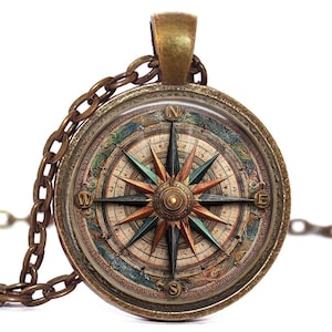 May include: A vintage-style compass pendant necklace. The round pendant features a detailed compass rose design with directional markers and a bronze-colored chain. The compass rose has shades of blue, green, and orange.