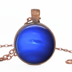May include: A copper chain necklace with a round pendant featuring a blue, swirling, abstract design.