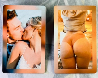 May include: Two rectangular metal photo cards with copper-toned borders. The left card displays a couple kissing, while the right card shows a person from behind wearing a tan shirt and tan underwear. Both cards feature a smooth, metallic finish.