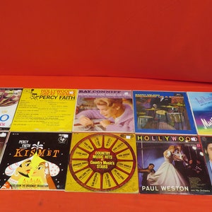 May include: A collection of ten vintage vinyl records with various artists and titles, including "Around the World in 80 Days", "Mantovani", "Kismet", "Hollywood's Great Themes", "Ray Conniff", "Hollywood", "Music & Memories", and "Country Music Hits".
