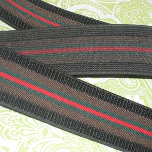 May include: Black elastic trim with brown, green, and red stripes. The trim has a textured surface.