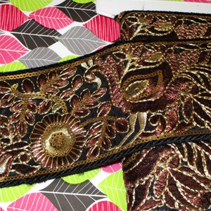 Könnte beinhalten: Schwarze und goldene Stickerei mit floralem Muster. Die Borte ist aus einem weichen, samtartig-weichen Stoff gefertigt und hat ein zartes, filigranes Design.